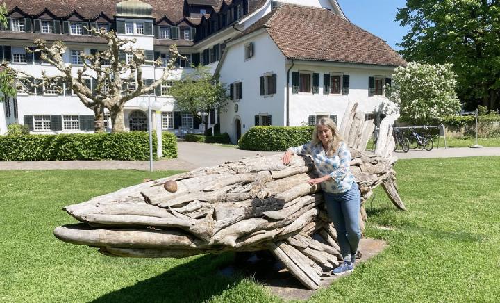 Caroline Schneider, Kommunikationsverantwortliche vom Reusspark, vor einer der Skulpturen aus Schwemmholz. Der Hecht entstand zum Fokusthema 2024 «Tierisch gut!» und schmückt das Reusspark-Gelände. Foto: mbe