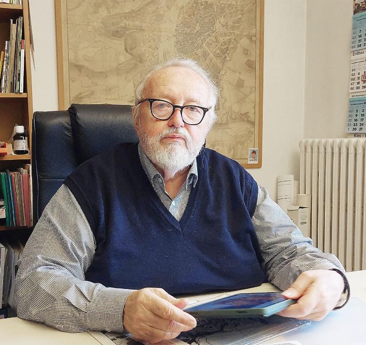 Tomas Masarik in seinem Büro. Hinter sich die historische Karte der Stadt Prag. Vor sich Pläne und Fotos aus früheren Zeiten. Foto: bg