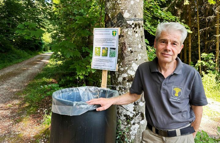 Marcel Humbel, Präsident der Forstkommission der Ortsbürgergemeinde Birmenstorf, steht im Wald neben einem Fass, in welches Waldbesuchende Neophyten wie Berufkraut, Goldrute oder Springkraut entsorgen können. Foto: hhs