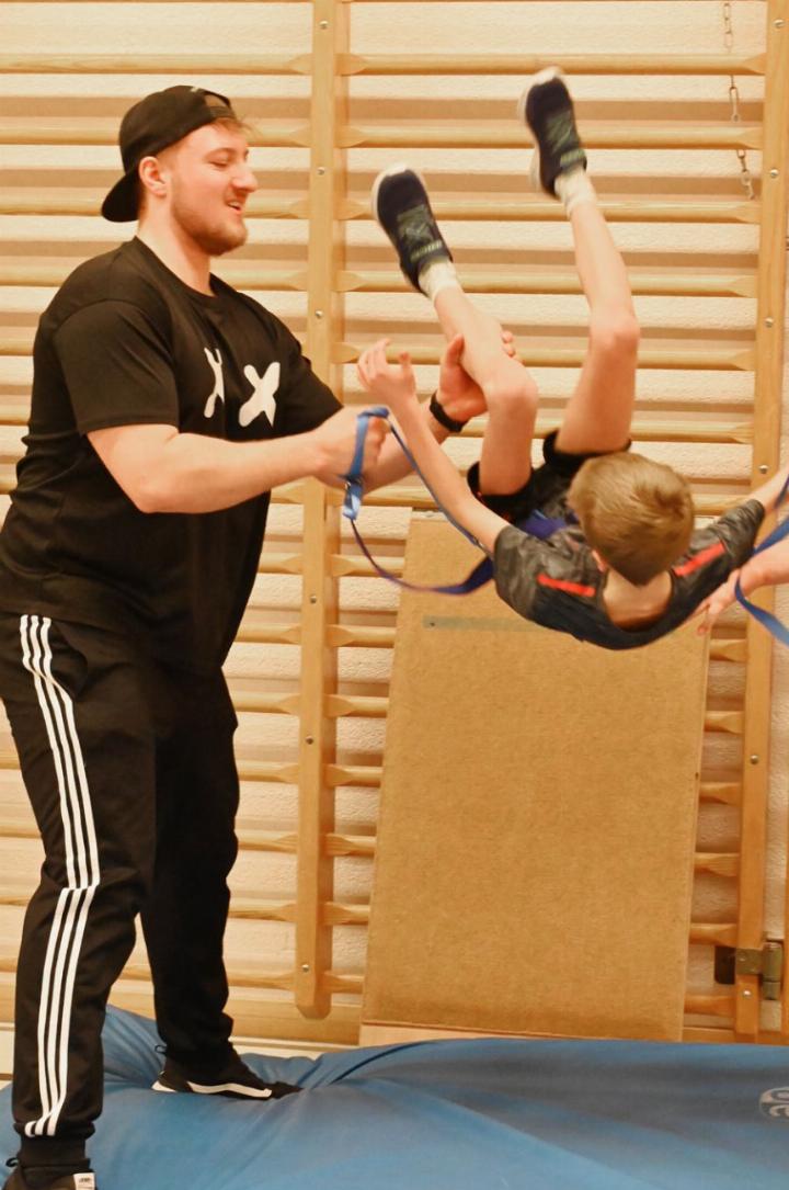 Trainer Jonathan Rudolf sichert die ersten Salto-Versuche.