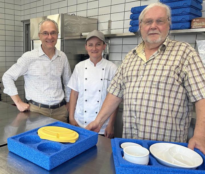 Manager René Holenweger, Köchin Claudia Etterlin und VAAS-Präsident Heinz Widmer (v. l. n. r.) in der Mägenwiler Produktionsküche vor einer Warmhaltebox, deren Porzellan Tag für Tag mit Speisen gefüllt wird. Fotos: hhs