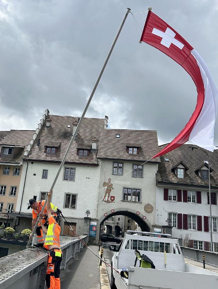 Severin Kamm (hinten) und ein Mitarbeiter setzen die Fahne. Foto: hhs