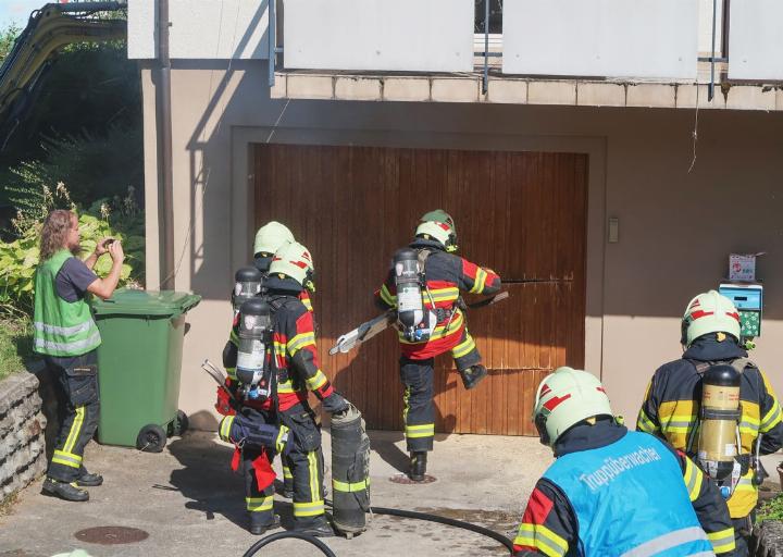 Die Feuerwehrmänner sägen ein Loch in die Garagentüre und treten diese ein.