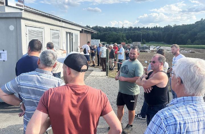 Neben dem Trafohäuschen beantwortet Toni Peterhans (rechts, mit Sonnenbrille) die Fragen von zahlreichen Besucherinnen und Besuchern zum Energiespeicher, der seinen Betrieb energieautark macht. Foto: hhs