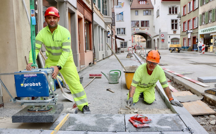 Die Luserna-Granitplatten werden von Strassenbautechniker Maik Roeber (rechts) millimetergenau verlegt. Polier Krist Nikolla (l.) schaut, dass der Bagger die Platten an die richtige Stelle hievt. Fotos: dg Die Luserna-Granitplatten werden von Strassenbautechniker Maik Roeber (rechts) millimetergenau verlegt. Polier Krist Nikolla (l.) schaut, dass der Bagger die Platten an die richtige Stelle hievt. Fotos: dg