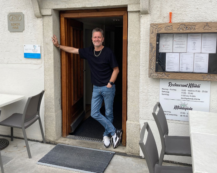 Deny Zurbuchen (55) vor dem Eingang des Restaurants Mühli, das er seit 2021 führt und zur Blüte gebracht hat. Rechts vom Hauptlokal befindet sich der beliebte Mühligade und die Sommer-Terrasse, die jetzt auf ist. Foto: mbe
